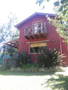 una casa roja con una ventana y algunas plantas en Cabañas "Lola Mora" en Tandil