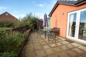 eine Terrasse mit Tisch und Stühlen und einem Sonnenschirm in der Unterkunft Goitre Bach Cottage in Aberaeron