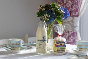 Eine Flasche Milch und zwei Tassen und eine Vase mit Blumen in der Unterkunft Goitre Bach Cottage in Aberaeron