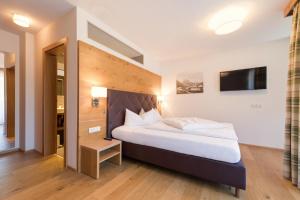 a bedroom with a large bed and a tv at Hotel Enzian Paznaun in See