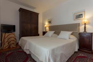 um quarto com uma grande cama branca e uma televisão em Quinta de São Caetano - São Miguel Açores em Populo