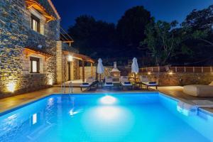 a swimming pool in front of a house at night at Faraggi Villas in Zonianá