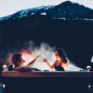 Ein Mann und eine Frau in einer Badewanne mit Gläsern Wein in der Unterkunft Historisches Hotel Bären in Kiental