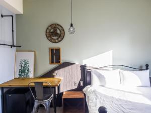 ein Schlafzimmer mit einem Bett, einem Tisch und einer Uhr in der Unterkunft Tra旅宿 in Taichung