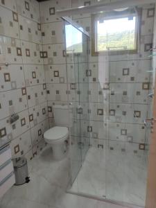 ein Bad mit einem WC und einer Glasdusche in der Unterkunft Chalés Costa Esmeralda, Bombinhas in Bombinhas