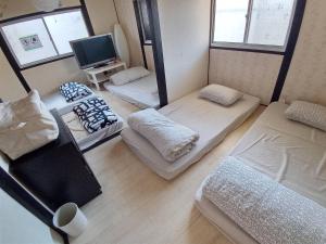 um pequeno quarto com três camas e uma televisão em Hakko Ichiu em Osaka