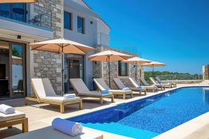 een zwembad met ligstoelen en parasols naast een gebouw bij Grand Resort Villa in Elefterna