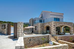 a house with a stone wall and a patio at Grand Resort Villa in Elefterna
