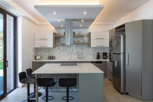 una cocina con armarios blancos y taburetes negros en Grand Resort Villa, en Elefterna