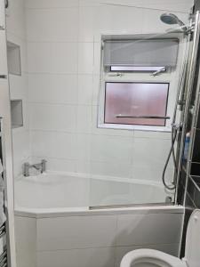 a bathroom with a tub and a toilet and a window at 24 Dryden Road - Beautiful 2 bed in Longley