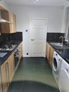 una cucina con porta bianca, lavatrice e lavandino di 24 Dryden Road - Beautiful 2 bed a Longley