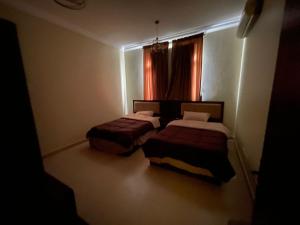 a dark room with two beds and a window at شاليه درة العروس in Durat Alarous