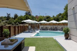 a swimming pool in a yard with chairs and umbrellas at Villa Chnaris - Private Pool and Sauna in Perama