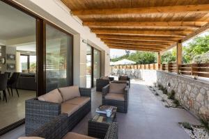 a patio with wicker furniture and a stone wall at Villa Chnaris - Private Pool and Sauna in Perama