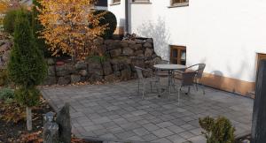 eine Terrasse mit einem Tisch, Stühlen und einer Steinmauer in der Unterkunft Ferienwohnung Gutwin in Bischofsheim an der Rhön