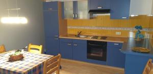 eine Küche mit blauen Schränken und einem Tisch mit Tischdecke in der Unterkunft Ferienwohnung Gutwin in Bischofsheim an der Rhön