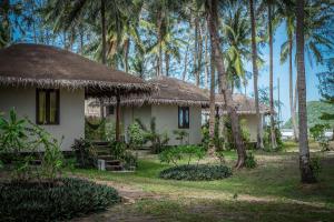 a house with a thatched roof and palm trees at Baan Manali Resort in Thongsala