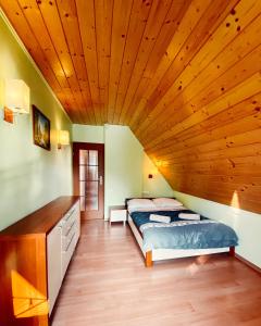 - une chambre avec un lit et un plafond en bois dans l'établissement Żywiecka Przystań, à Żywiec