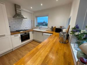 a kitchen with white cabinets and a wooden table at Pass The Keys Beautiful 3 Bedroom House with Great Views of Bath in Bath