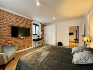 a bedroom with a brick wall and a bed and a tv at Miodowa Faktoria # 4 in Toruń