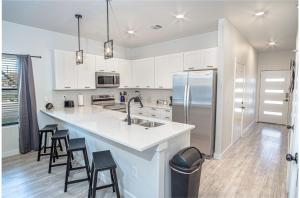 a kitchen with white cabinets and a large island with bar stools at Spectacular 3 BR plus 2 and a half BA Apt Near Downtown in San Antonio