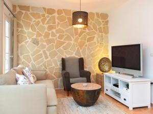 ein Wohnzimmer mit einem TV, einem Sofa und einem Stuhl in der Unterkunft Holiday Home Residencial Bel-Air by Interhome in Calpe