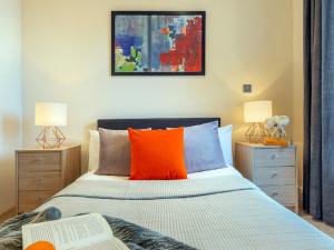 a bedroom with a bed with an orange pillow at Apartment Canary Gateway- Canary Wharf by Interhome in London