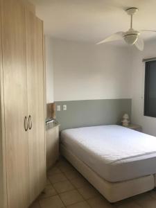 um quarto com uma cama branca e um armário de madeira em BEIRA DA PRAIA com VISTA TOTAL DO MAR em Florianópolis