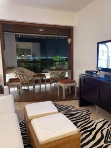 - un salon avec une télévision, une table et des chaises dans l'établissement BEIRA DA PRAIA com VISTA TOTAL DO MAR, à Florianópolis