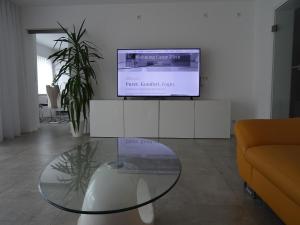 a living room with a glass table and a tv at Ferienwohnung HappyNES in Bad Neustadt an der Saale