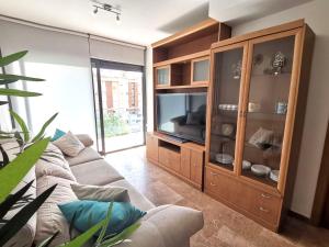 een woonkamer met een bank en een entertainmentcentrum bij Precioso apartamento 4 habitaciones con piscina y gym in Lloret de Mar