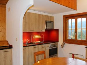 une cuisine avec des placards en bois, une table et une fenêtre dans l'établissement Chalet Chalet 4 pièces 969 by Interhome, à Moleson