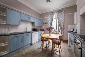 a kitchen with blue cabinets and a table with chairs at St Kitts Holiday Apartment in Filey