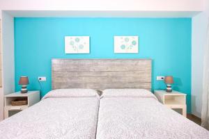 1 dormitorio con 1 cama grande y pared azul en Marcos Apartment en Port de Pollensa