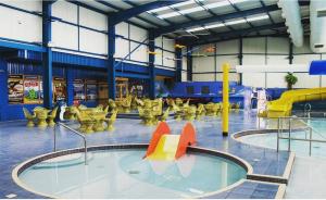 a swimming pool in a building with a water park at Cosy caravans Meadow lake Golden Palm Resort in Chapel Saint Leonards