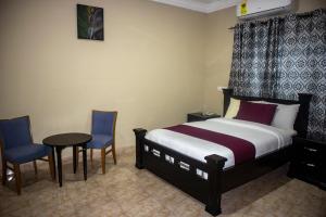 Pantang的住宿－Kislas Luxury Hotel，一间卧室配有一张床、两把椅子和一张桌子