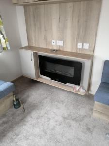 a living room with a fireplace and a blue couch at 69R Seawick 2 Bedroom Caravan . New for 2022 in Saint Osyth