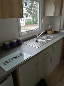 a kitchen counter with a sink and a window at 69R Seawick 2 Bedroom Caravan . New for 2022 in Saint Osyth