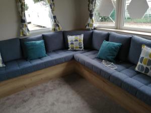 a blue couch in a room with windows at 69R Seawick 2 Bedroom Caravan . New for 2022 in Saint Osyth