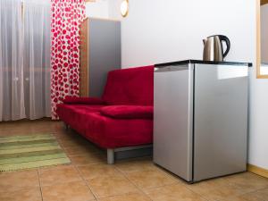 a living room with a red couch and a refrigerator at Malinowy Dworek - Spokojny wypoczynek nad morzem in Ciekocino +17 photos