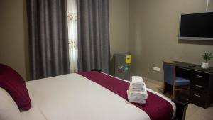 Pantang的住宿－Kislas Luxury Hotel，酒店客房配有一张床、一张书桌和一台电视。