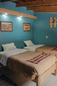 two beds in a room with blue walls at Doña Catta Casa Boutique in Ollantaytambo