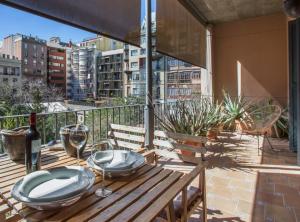 a table with plates and wine glasses on a balcony at BCN Rambla Catalunya Apartments in Barcelona