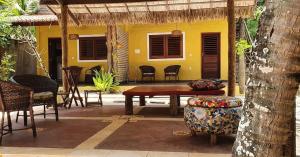 una casa amarilla y un patio con mesa y sillas. en Moringa Beach, en São Miguel do Gostoso