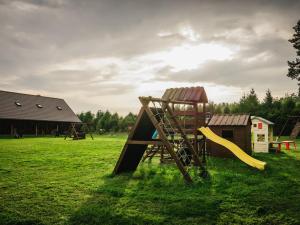 a playground in a field with a slide at Malinowy Dworek - Spokojny wypoczynek nad morzem in Ciekocino