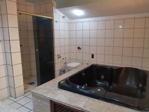 a bathroom with a black tub and a toilet at Residencial Samuel in Bombinhas +33 photos
