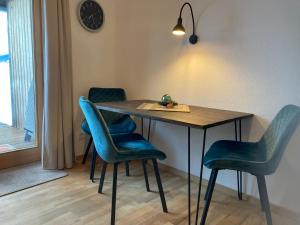 ein Esstisch mit blauen Stühlen und einer Uhr in der Unterkunft Alpenflair Ferienwohnung 231 Mina's Gipfelliebe in Oberstdorf