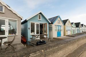 a row of blue and white houses in a row at Stargazing Beach Hut on Mudeford Sandbank with wake up sea views in Christchurch