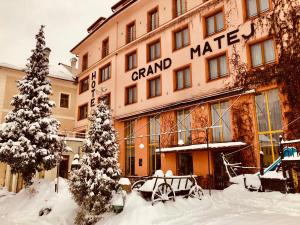 a building with a sign on it in the snow at Hotel & Penzión Grand Matej in Banská Štiavnica