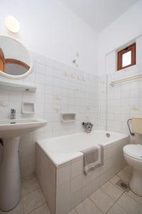 a bathroom with a tub and a sink and a toilet at Adonis Hotel in Agia Galini